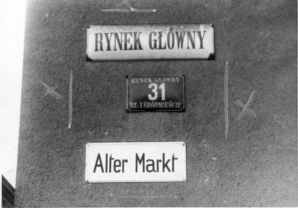 Do pierwszej rocznicy napaści hitlerowskiej na Polskę Rynek Główny nosił nazwę „Alter Markt” (Stary Targ), zachowując jeszcze – dla łatwiejszej identyfi kacji – stare polskie tabliczki (jak wiele ulic), ale 1 września 1940 roku przemianowano go uroczyście na „Adolf Hitler Platz”, umieszczając duże tablice i likwidując wszystkie inne tabliczki. Fot. przedstawia „przymiarkę” do rozmiarów tablicy Hitlera